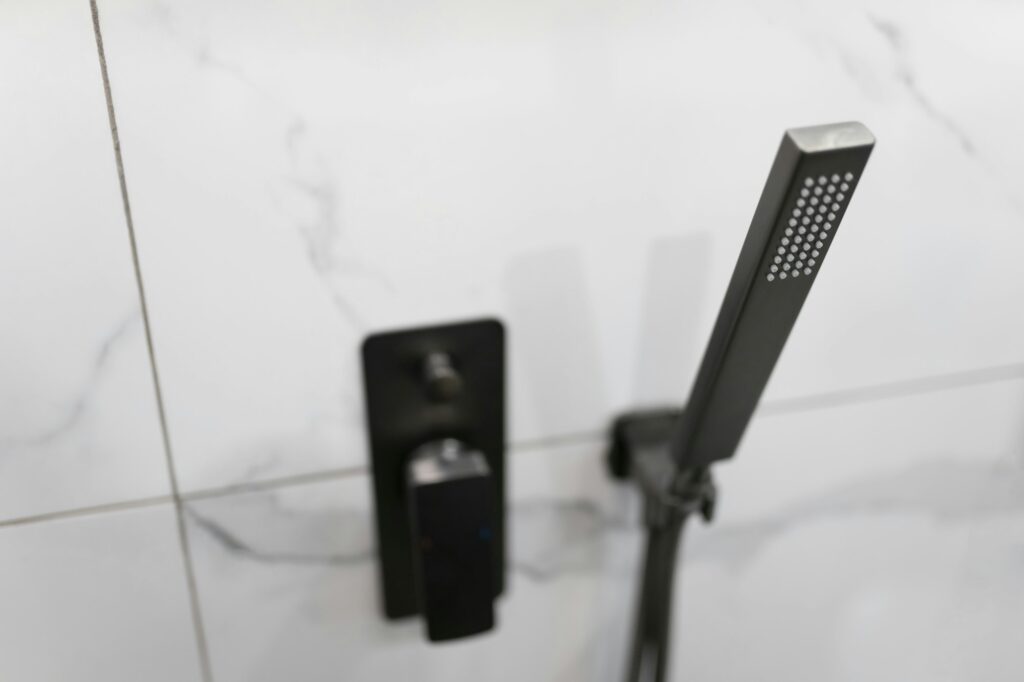 Faucet and shower head on the tile wall in the bathroom