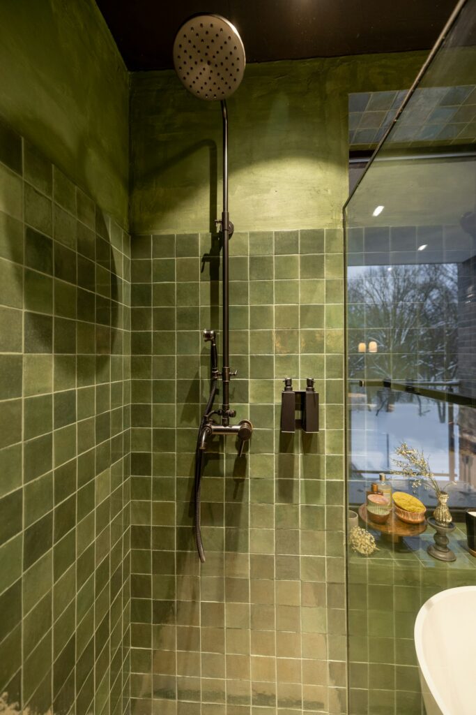 Shower with green tiles and black faucet