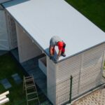 Worker Installing Roof on Wooden Shed